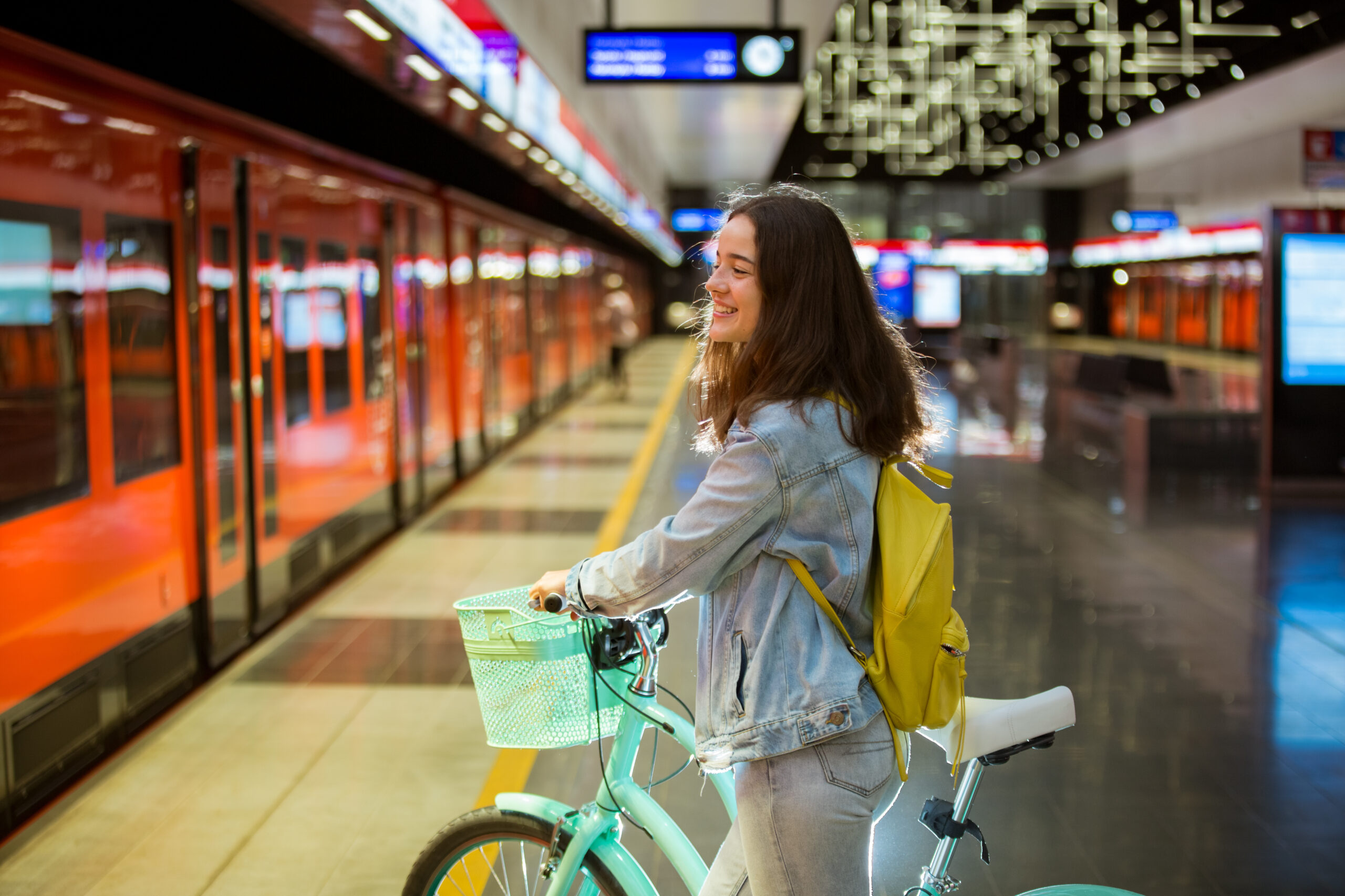 Teenager girl in jeans with yellow backpack and bike standing on